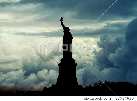 Silhouette of Statue of Liberty over dramatic... - Stock Photo