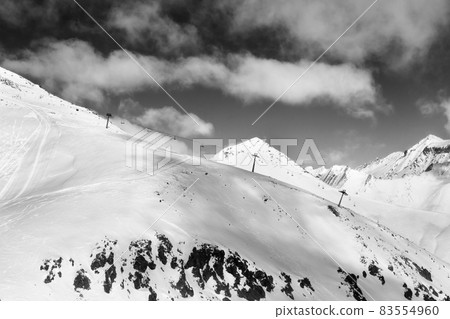 Off-piste slope and chair-lift on ski resort. Black and white toned landscape. Off-piste slope and chair-lift on ski resort. Black and white toned landscape. 83554960