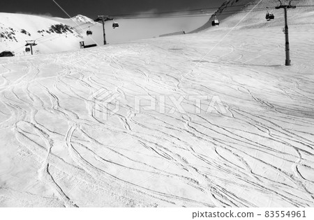 Snowy ski slope with trace from skis and snowboards. Black and white toned landscape. Snowy ski slope with trace from skis and snowboards. Black and white toned landscape. 83554961
