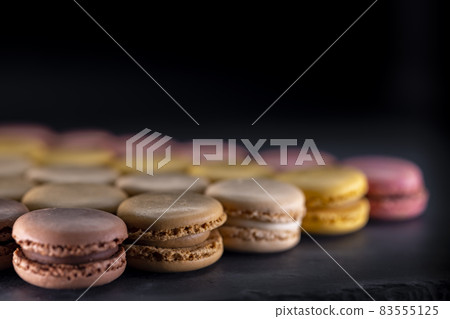 chocolate, coffee, vanilla, lemon and strawberry macaroons on black background chocolate, coffee, vanilla, lemon and strawberry macaroons on black background 83555125