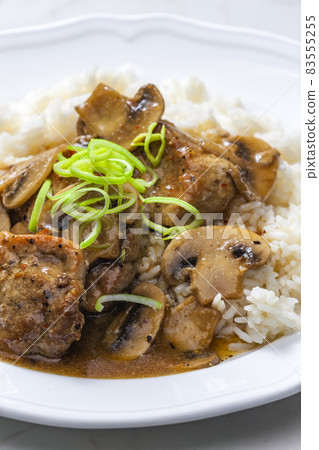 slices of pork meat with mushrooms and gravy served with rice 83555255