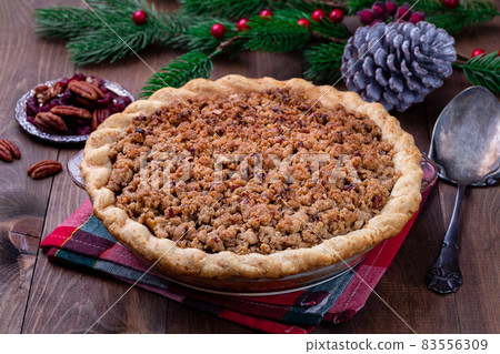 Freshly baked American apple cranberry pie, topped with crumbled dough and pecan, in baking dish Freshly baked American apple cranberry pie, topped with crumbled dough and pecan, in baking dish 83556309
