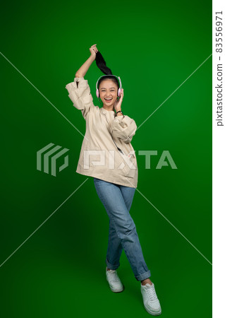 young girl with long hair wearing headphones listening to music with cheerful expression while hands raised young girl with long hair wearing headphones listening to music with cheerful expression while hands raised 83556971