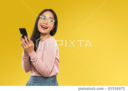 attractive woman in glasses smiling while using a mobile phone 83556973