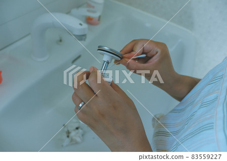 Housewife cleaning the drain of the washbasin 83559227