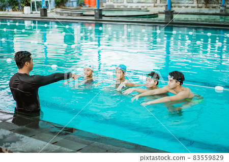 an instructor in the pool pointing while lecturing four teenagers 83559829