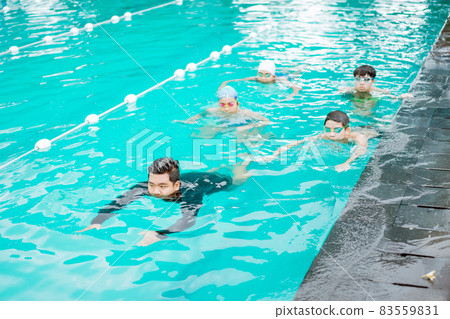 an instructor gives an example of how to swim in a pool to four teenagers 83559831