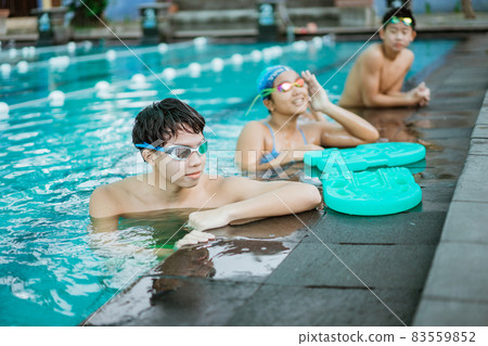 a teenage boy in swimming goggles while standing in the pool a teenage boy in swimming goggles while standing in the pool 83559852