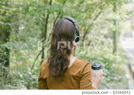 A woman listening to music in the fresh green A woman listening to music with headphones A woman listening to music in the fresh green A woman listening to music with headphones 83560051
