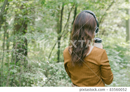 A woman listening to music in the fresh green A woman listening to music with headphones A woman listening to music in the fresh green A woman listening to music with headphones 83560052