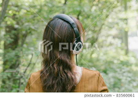 A woman listening to music in the fresh green A woman listening to music with headphones A woman listening to music in the fresh green A woman listening to music with headphones 83560061