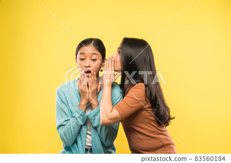 a girl is very shocked when her friend talks whispering in her ear a girl is very shocked when her friend talks whispering in her ear 83560184