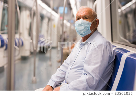 Old man in face mask sitting inside subway train Old man in face mask sitting inside subway train 83561035