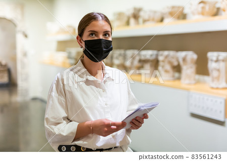 Woman in mask visiting exhibit at sculpture hall in museum 83561243