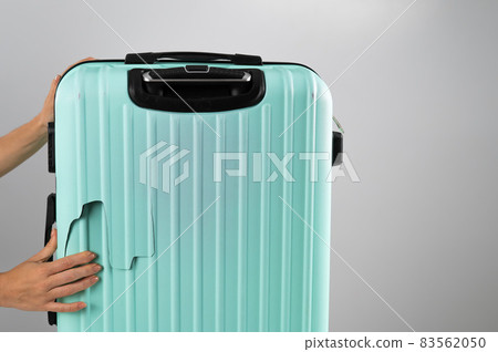 A woman demonstrates a broken suitcase on a white background. Damaged baggage during the flight. 83562050