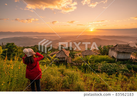 Back view of tourist woman traveling and looking to beautiful sunrise view of the mountains range on Doi Sango (or Sa-Ngo) mountain in Chiang Saen district of Chiang Rai province of Thailand. 83562183