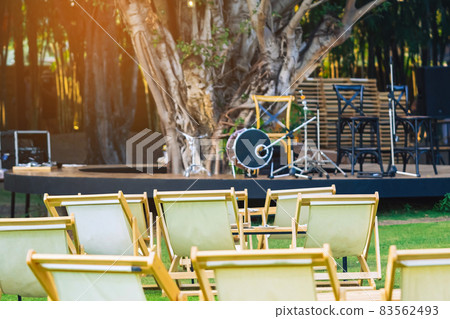 Many empty white deck chairs with tables in lawn is surrounded by shady green grass. Comfortable on outdoor patio chairs in garden. Lawn chairs in the park. Sunbeds in the garden. Selective focus. Many empty white deck chairs with tables in lawn is surrounded by shady green grass. Comfortable on outdoor patio chairs in garden. Lawn chairs in the park. Sunbeds in the garden. Selective focus. 83562493