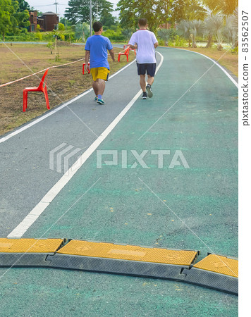 Black and yellow heavy plastic covers for people and vehicle to cross over cables laid on road. Pavement pads to protect electrical wiring on sidewalk in public park. Channel for laying the wires. Black and yellow heavy plastic covers for people and vehicle to cross over cables laid on road. Pavement pads to protect electrical wiring on sidewalk in public park. Channel for laying the wires. 83562507