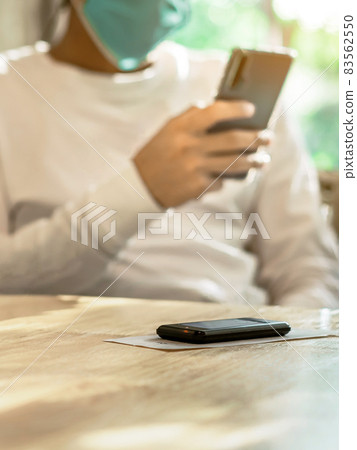 Queue Wireless Calling System Restaurant or Pager Customers System with invoice on table with blur image of man wear protective face mask using cellphone in background. Alarm signal when food is done. 83562550