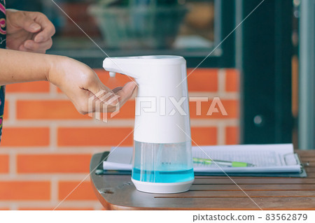 Automatic alcohol dispenser for cleaning hand to prevent the spreading of Coronavirus (Covid-19) on table before entrance to cafeteria. Healthcare concept. New normal lifestyle. Selective focus Automatic alcohol dispenser for cleaning hand to prevent the spreading of Coronavirus (Covid-19) on table before entrance to cafeteria. Healthcare concept. New normal lifestyle. Selective focus 83562879