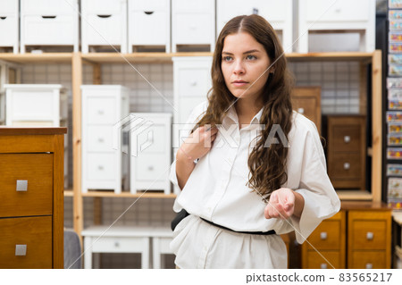 Female choosing wooden drawer in furniture store 83565217