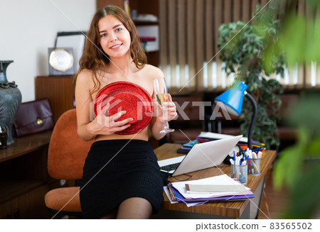 Photo of Woman sitting half-nude at a table with a glass of wine covering  her bared breast