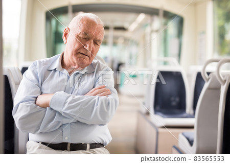 Elderly man sitting in tram and sleeping Elderly man sitting in tram and sleeping 83565553