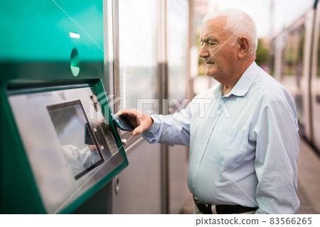 Old man using cash machine with smartphone 83566265