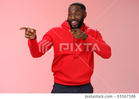 Hey mate what up. Portrait cheeky confident outgoing african american bearded man entering club see friends make hello gesture pointing left finger pistols sassy smiling, standing pink background 83567386