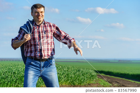 a man as a farmer walking along the field, dressed in a plaid shirt and jeans, checks and inspects young sprouts crops of wheat, barley or rye, or other cereals, a concept of agriculture and agronomy a man as a farmer walking along the field, dressed in a plaid shirt and jeans, checks and inspects young sprouts crops of wheat, barley or rye, or other cereals, a concept of agriculture and agronomy 83567990