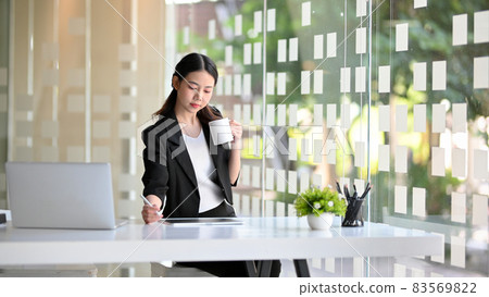 Business woman drinking coffee during working on tablet computer. Business woman drinking coffee during working on tablet computer. 83569822
