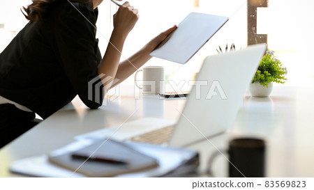 Female boss leaning on table and looking on tablet screen. Female boss leaning on table and looking on tablet screen. 83569823