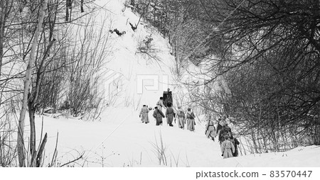 Men Dressed As White Guard Soldiers Of Imperial Russian Army In Russian Civil War Times Marching Through Snowy Winter Forest. Historical Reenactment 1917-1922. Black And White Photo 83570447
