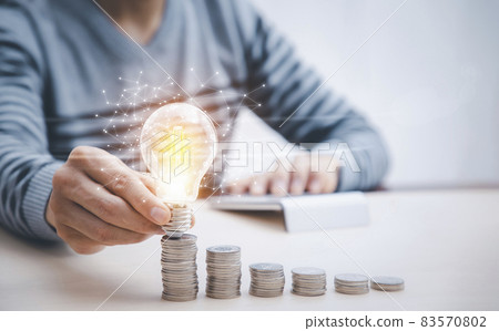 Businessman hand holding light bulb on coins stack on the wooden table , Saving ideas and investment budget, Creative ideas concept of saving money concept, Copy space Businessman hand holding light bulb on coins stack on the wooden table , Saving ideas and investment budget, Creative ideas concept of saving money concept, Copy space 83570802