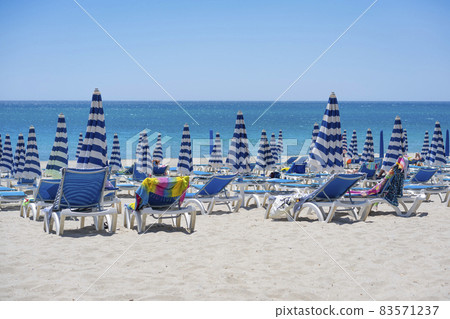 Blue and white umbrella and beachchair at the beach Blue and white umbrella and beachchair at the beach 83571237
