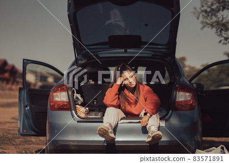 Attractive young woman resting in the trunk of a car 83571891