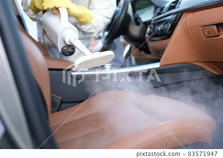 The specialist cleans the chair in the car with a washing vacuum cleaner 83571947