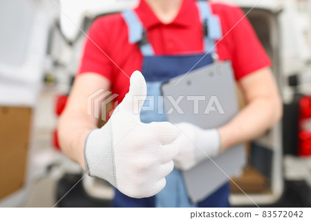 Male courier shows hand in glove gesture ok Male courier shows hand in glove gesture ok 83572042