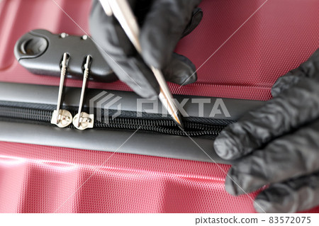 Gloved hands mending a snake on a suitcase Gloved hands mending a snake on a suitcase 83572075