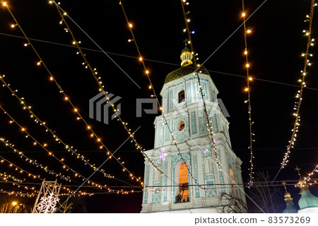 Beautiful scenic decorated Christmas Tree with decorations and illuminated by light garlands against Sophia Cathedral on background Sofievska square market. Happy 2022 New Year and xmas Celebration 83573269