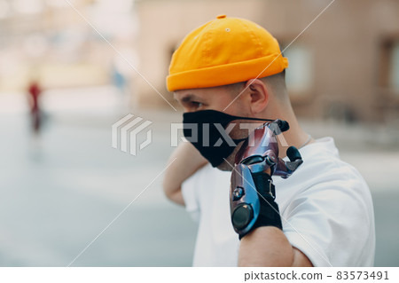 Young disabled man put on medical protective face mask with artificial prosthetic hand. 83573491