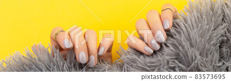 Womans hands holding furry fabric on yellow background Womans hands holding furry fabric on yellow background 83573695