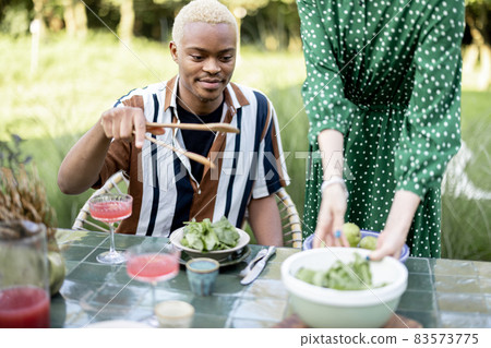 Woman put salad on plate of boyfriend at dinner Woman put salad on plate of boyfriend at dinner 83573775