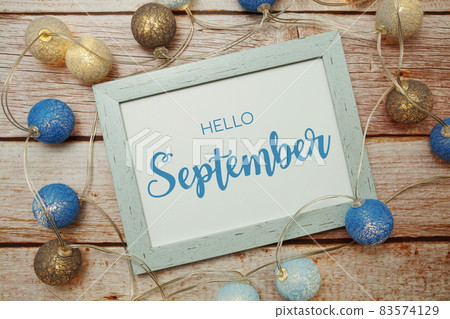 Hello September card typography text with LED cotton ball on wooden background Hello September card typography text with LED cotton ball on wooden background 83574129
