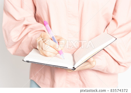 Women's hand writing notes in a notebook Women's hand writing notes in a notebook 83574372