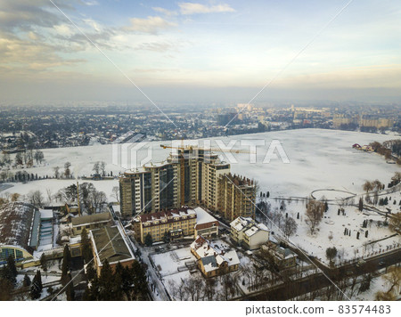 Apartment or office building under construction, aerial view. Tower crane silhouette on blue sky copy space background. Apartment or office building under construction, aerial view. Tower crane silhouette on blue sky copy space background. 83574483