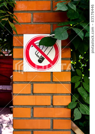 No smoking sign on a brick wall in a public place. Concept of banning smoking in public places, dangers and addictions of smoking. Vertical photo 83576446