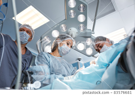 Concentrated Surgical team operating a patient in an operation theater. Well-trained anesthesiologist with years of training with complex machines follows the patient throughout the surgery 83576681
