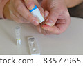 The woman uses a lancing device to take a blood sample from her finger 83577965