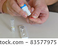 The woman uses a lancing device to take a blood sample from her finger 83577975